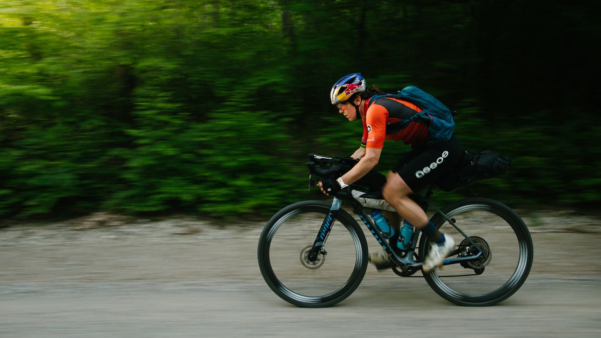 A female athlete riding a gravel bike along a trail