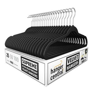 A stack of black velvet clothes hangers on a white cardboard box. 