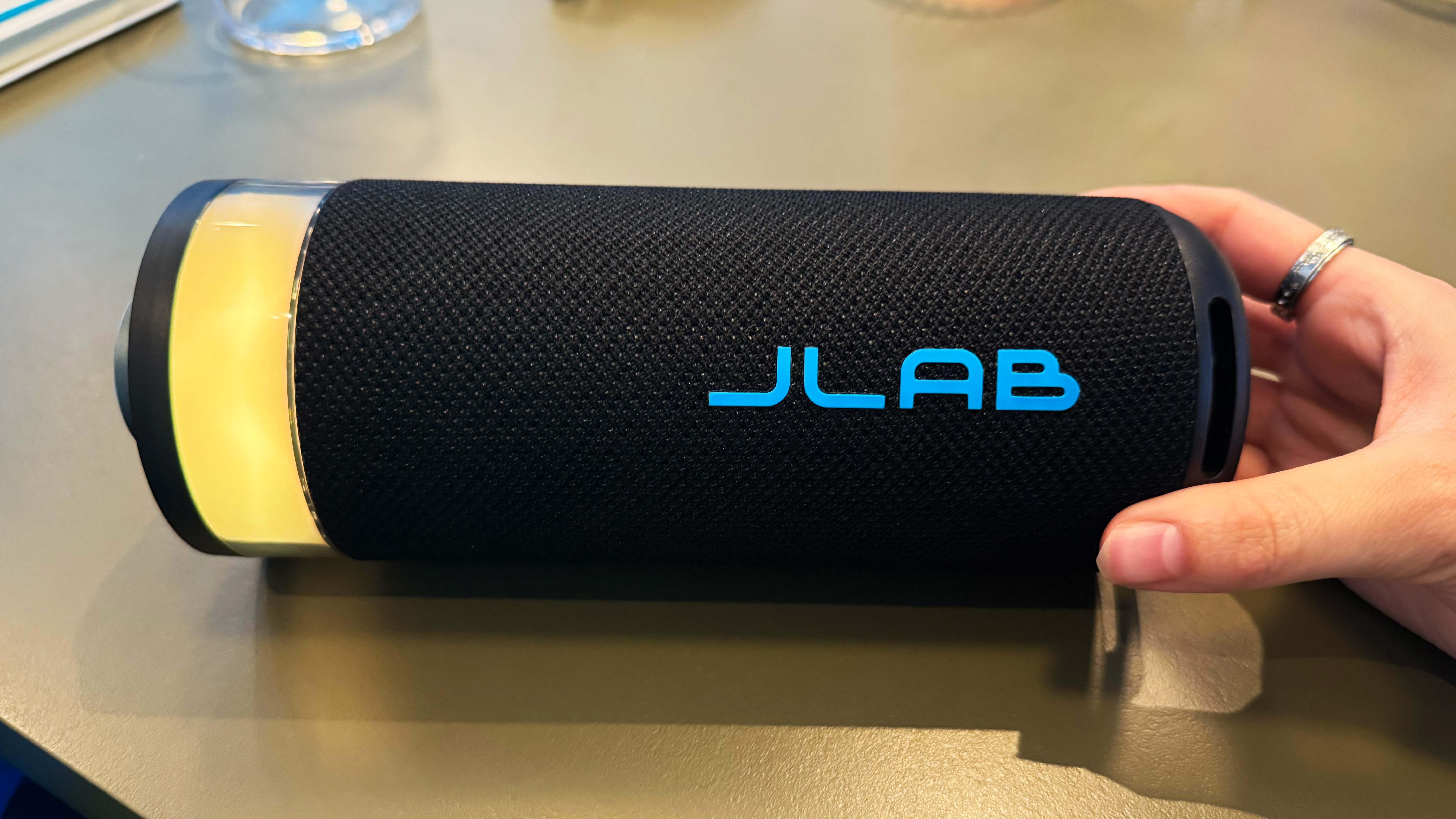 the jlab go party speaker with yellow LED and author's hand in the picture holding the speaker