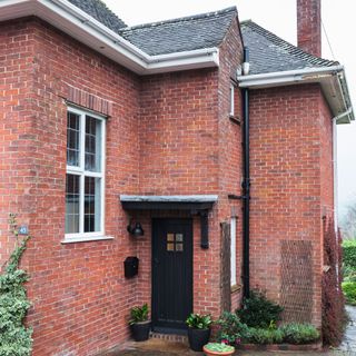 Red brick house exterior with black door and roof