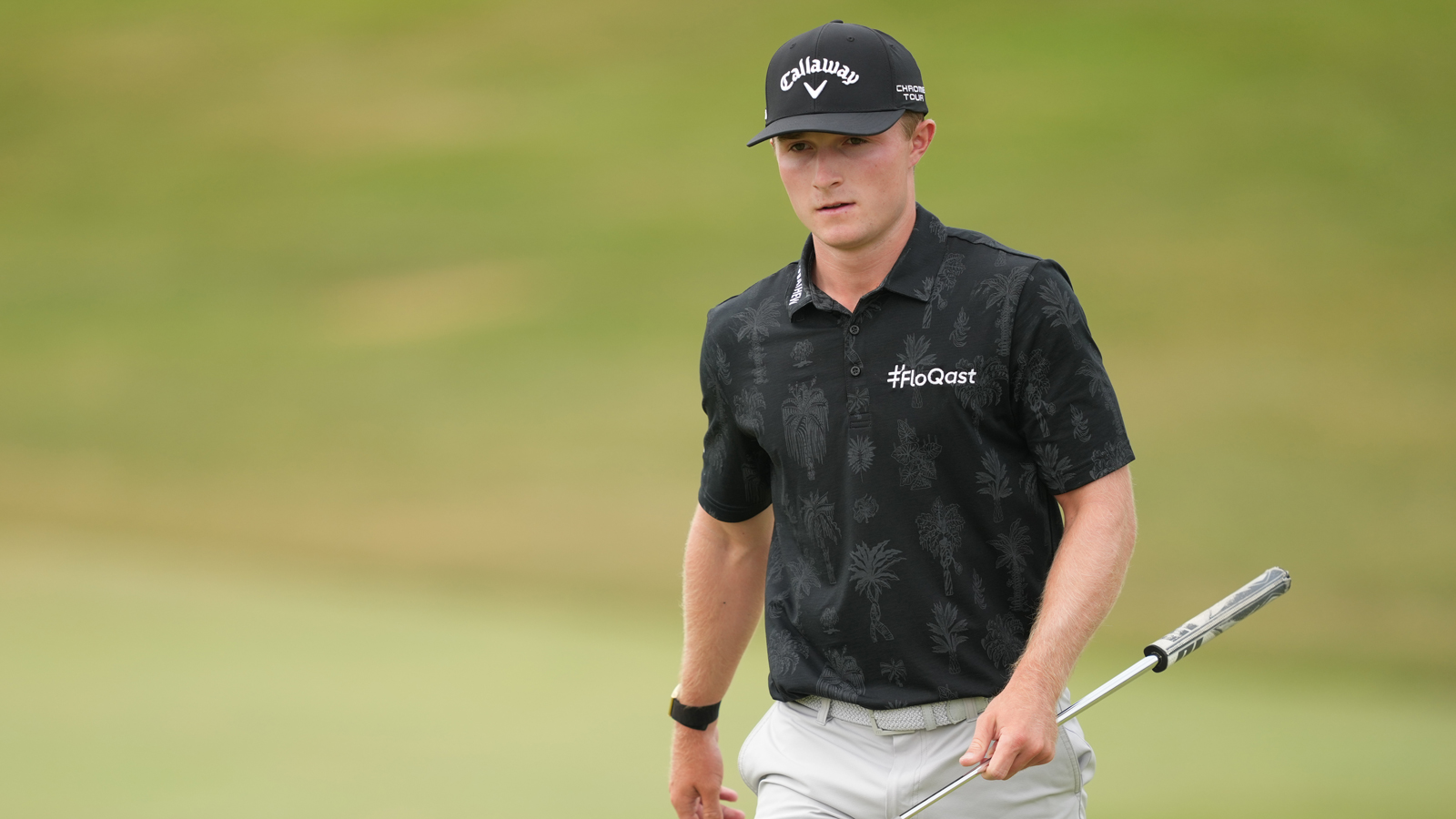 Blades Brown walks on the green holding a putter