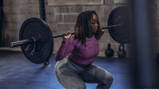 Woman doing a squat with barbell as part of the 5x5 workout