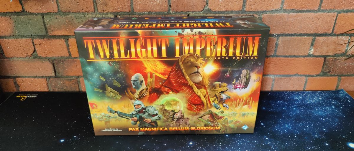 Twilight Imperium box on a starry surface, against a brick background