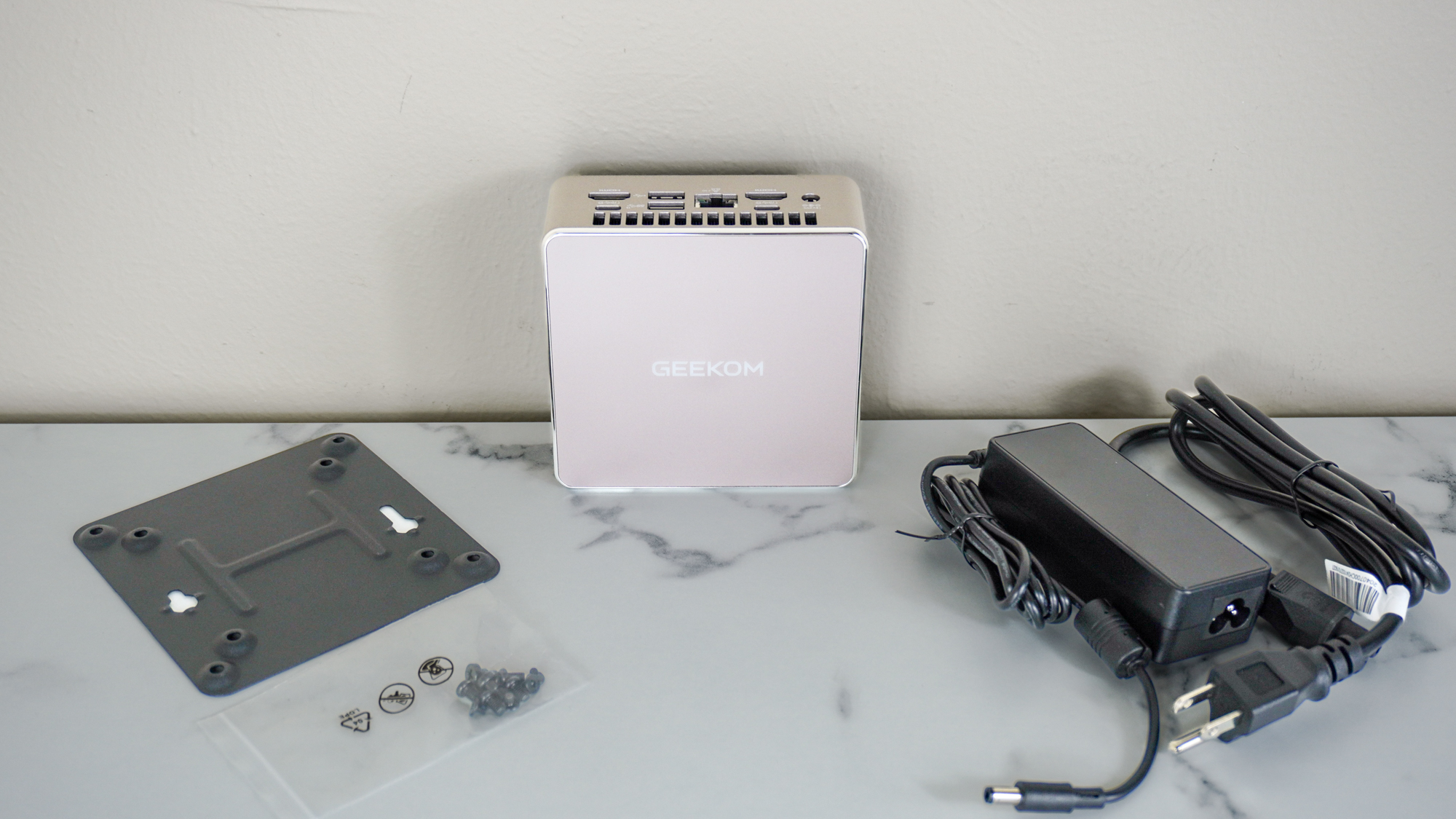 The Geekom A5 min PC with its power adapter and the included VESA mounting kit