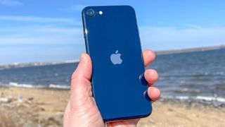 iPhone SE 2022 in hand at beach Midnight color