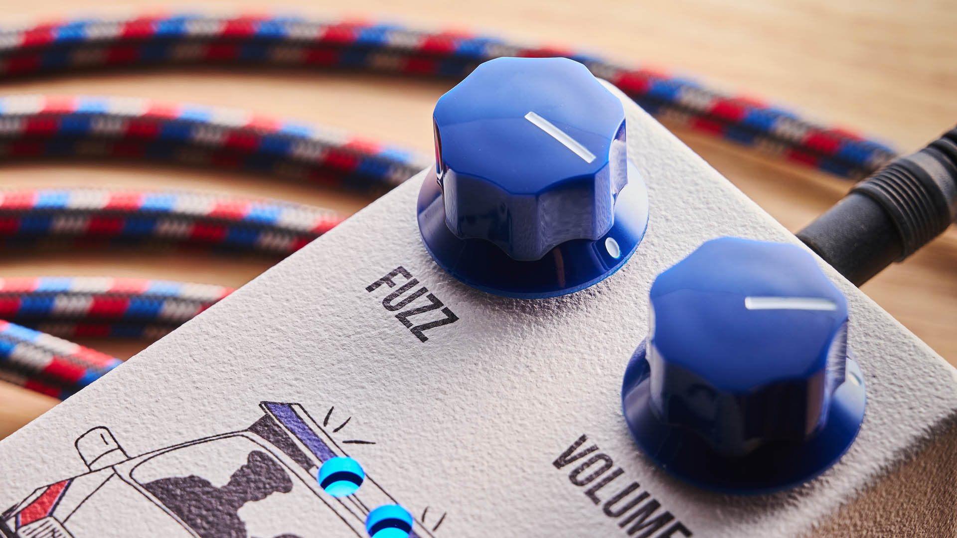 Funny Little Boxes Caught By The Fuzz: inspired by Supergrass, this two-knob fuzz has a white enclosure, blue dials, and a comic graphic of someone being apprehended in a police car.