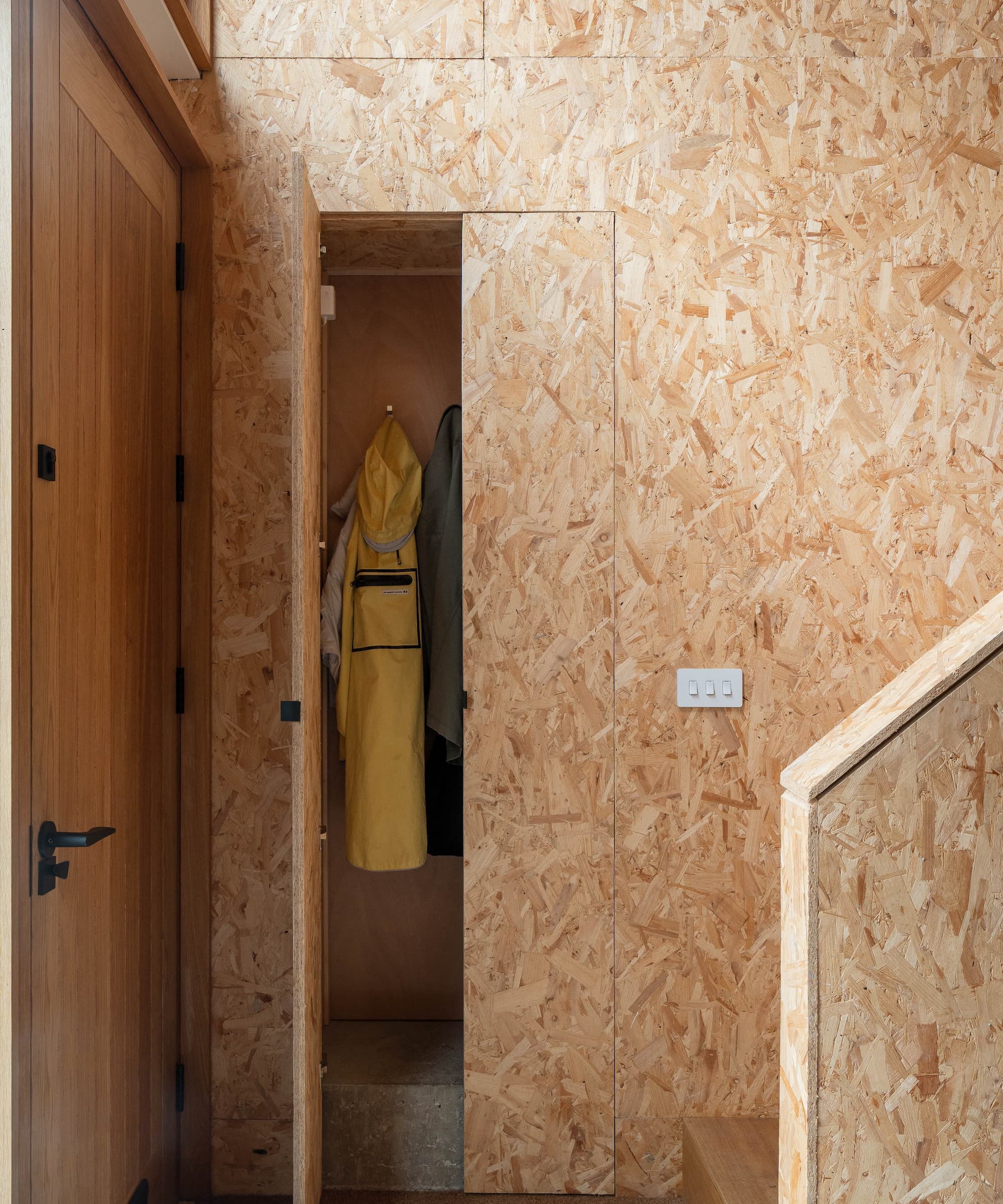 A plywood cupboard inbuilt into the wall at the bottom of the stairs