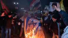 Iranian protesters are carrying a portrait of Iran's Supreme Leader Ayatollah Ali Khamenei and a Yemeni flag as they burn an Israeli flag during an anti-U.S. and anti-British protest in front of the British embassy in Tehran