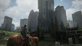 A horseback rider approaching a cityscape in a screenshot from the The Last of Us Part II