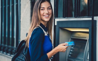 Young woman at ATM outside of bank