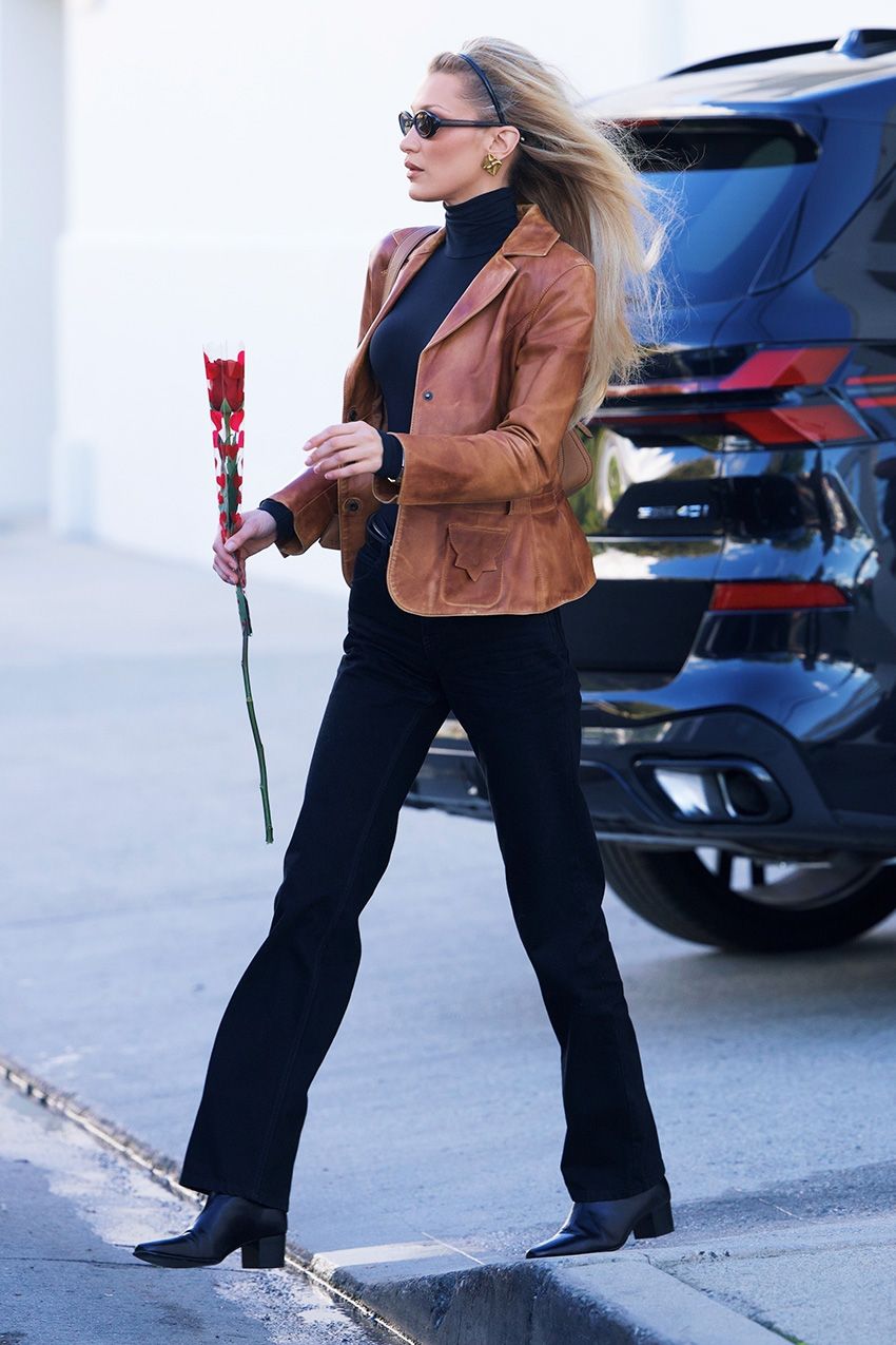 Bella Hadid wearing a brown leather jacket, black turtleneck, bootcut jeans, and block-heel boots