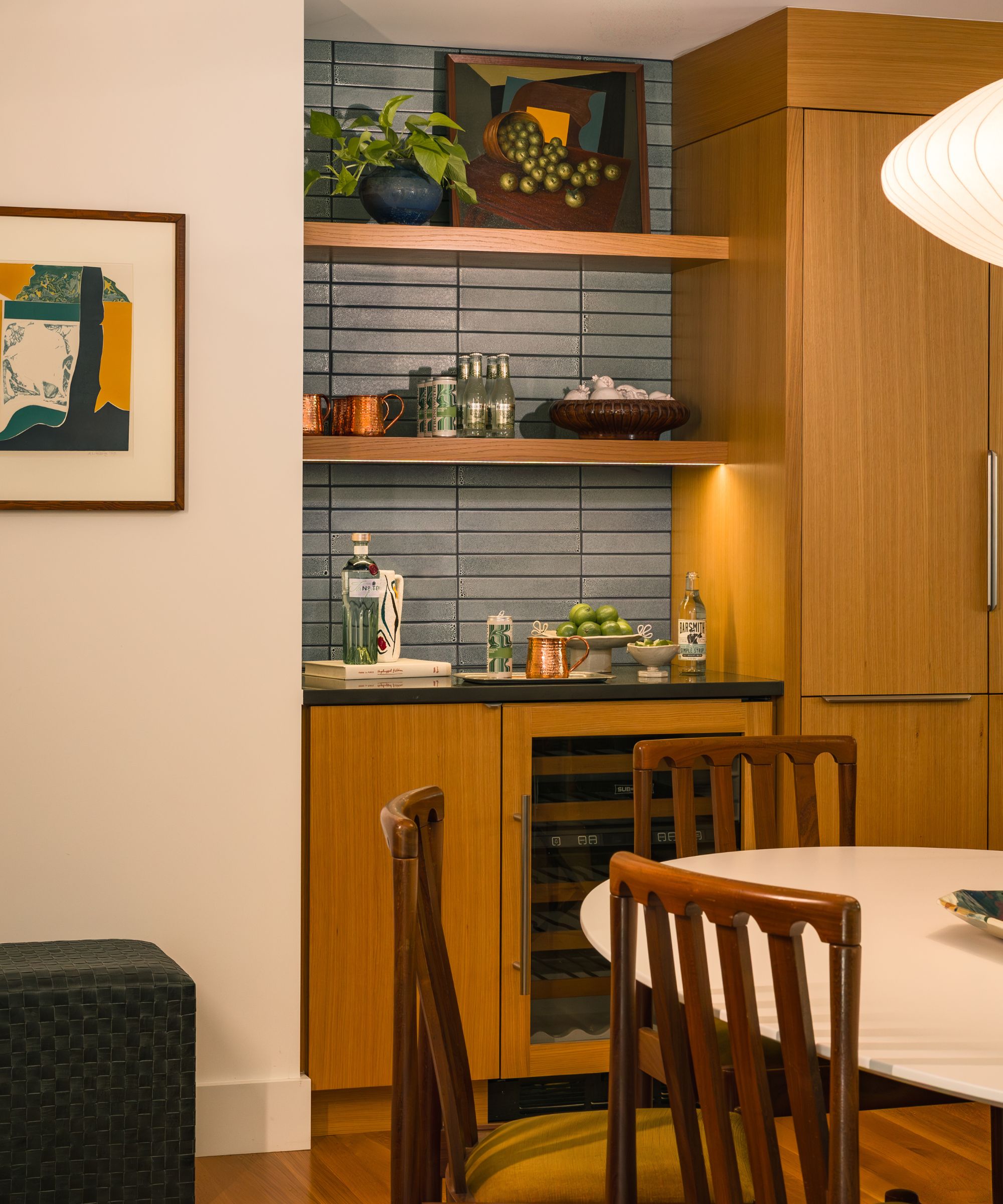 A small kitchen with wooden cabinets, wood floating shelves, and blue wall tiles