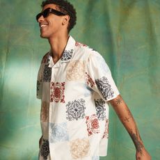 Male model wearing a patterned shirt and sunglasses sold at The Hut