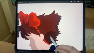 A hand drawing a colour block sketch of Kiki from Kiki's Delivery Service with an Apple Pen onto an iPad Pro