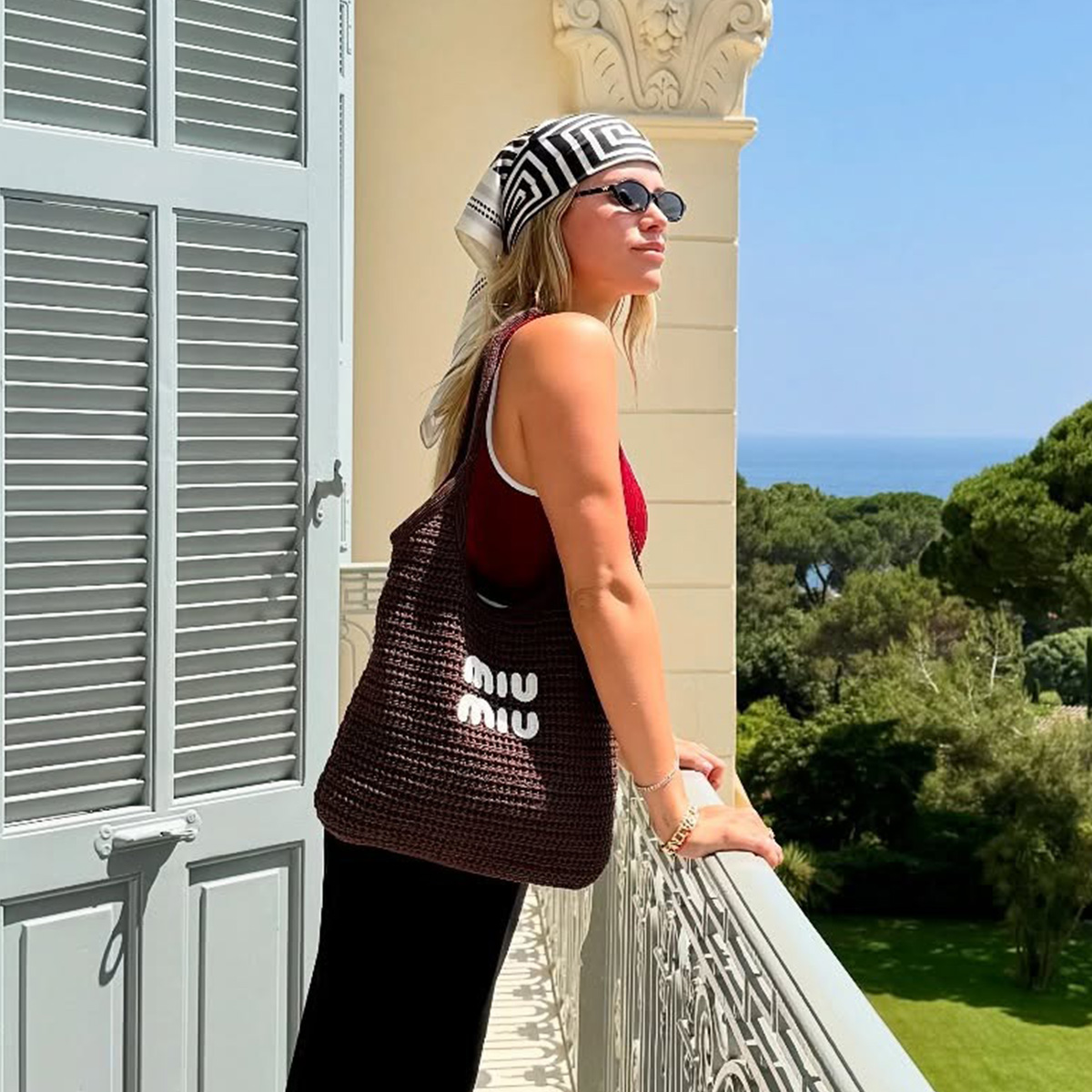 Sofia Richie Grainge in the French Riviera wearing a Gucci burgundy one-piece swimsuit, black pants, red flip flops, a brown Miu Miu bag, and a silk scarf.