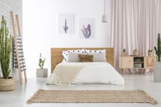 A bedroom with a large bed, cactus artwork, and a woven rug