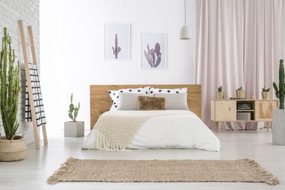 A bedroom with a large bed, cactus artwork, and a woven rug