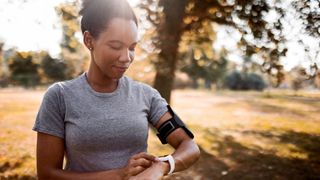 Woman checking fitness tracker on wrist, working out early in the morning