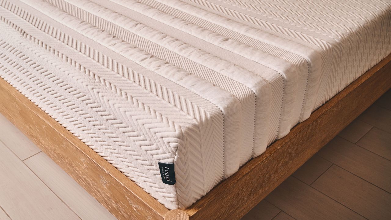 A closeup of the corner of the Leesa Legend Hybrid mattress, showing the striped design and the cover, plus the Leesa tag