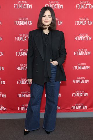 Selena Gomez wearing a black blazer and dark denim jeans on the red carpet