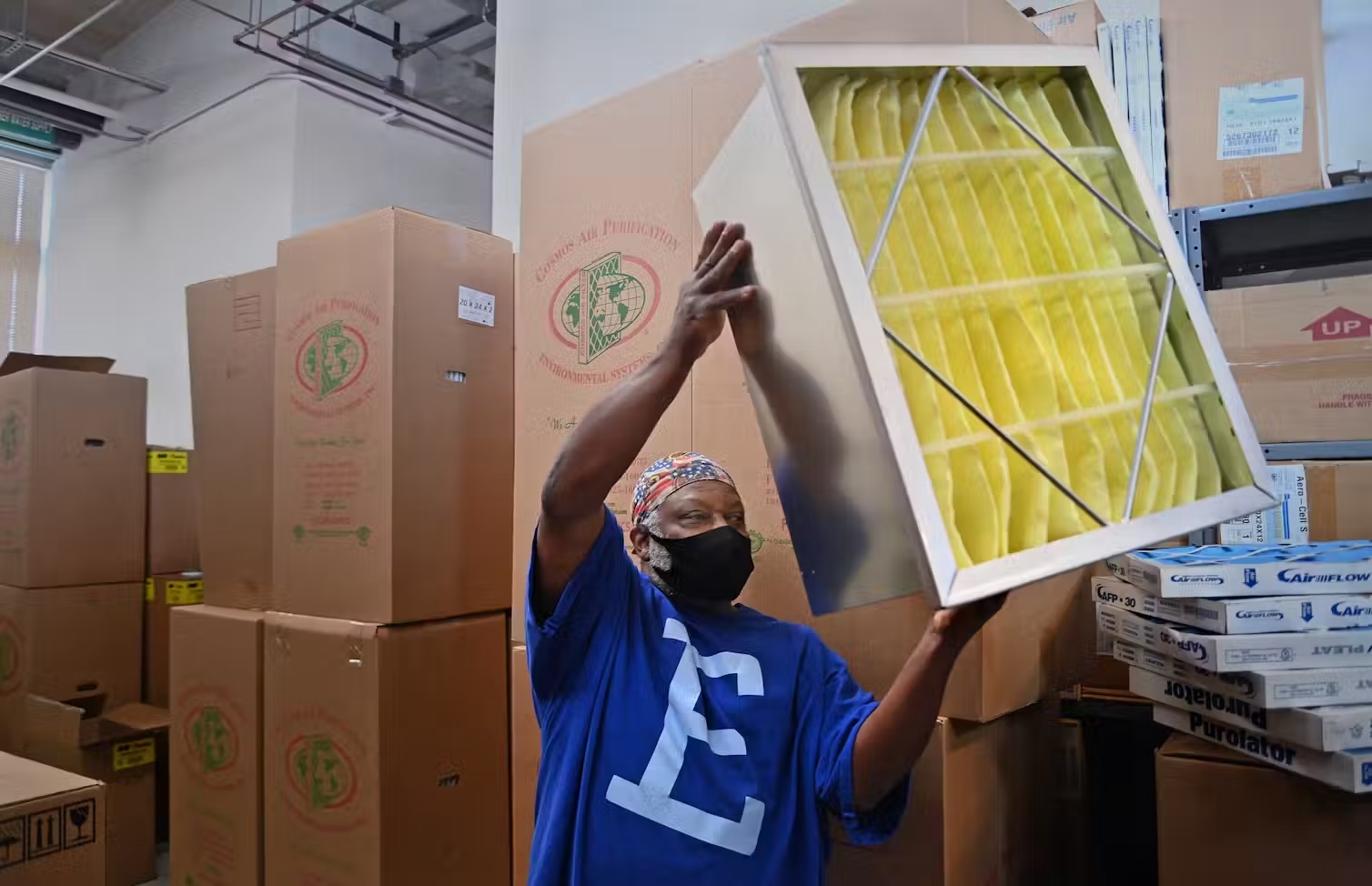 Man amongst boxes and holding an air filter.