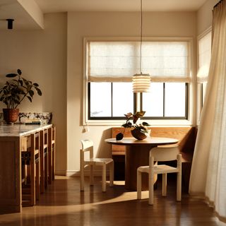 a kitchen diner with blinds on windows and curtains across a door