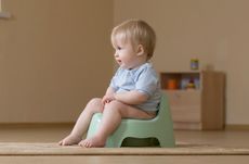 A child potty training and looking off camera to parents learning how to potty train.