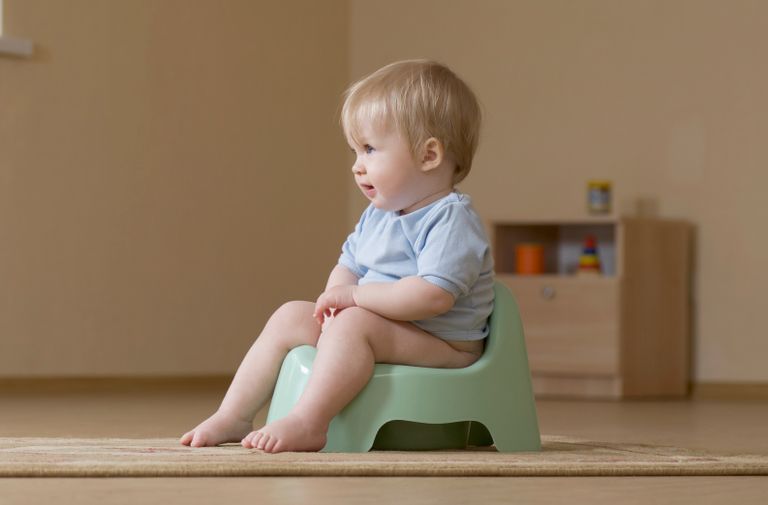 A child potty training and looking off camera to parents learning how to potty train.