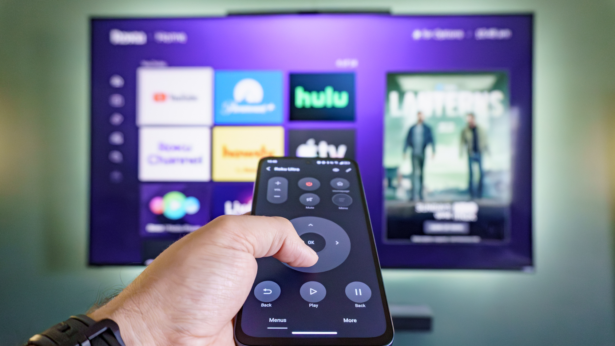 A person holding up the TCL NXTPAPER 70 Pro with TCL's IR Remote app open to control their TV