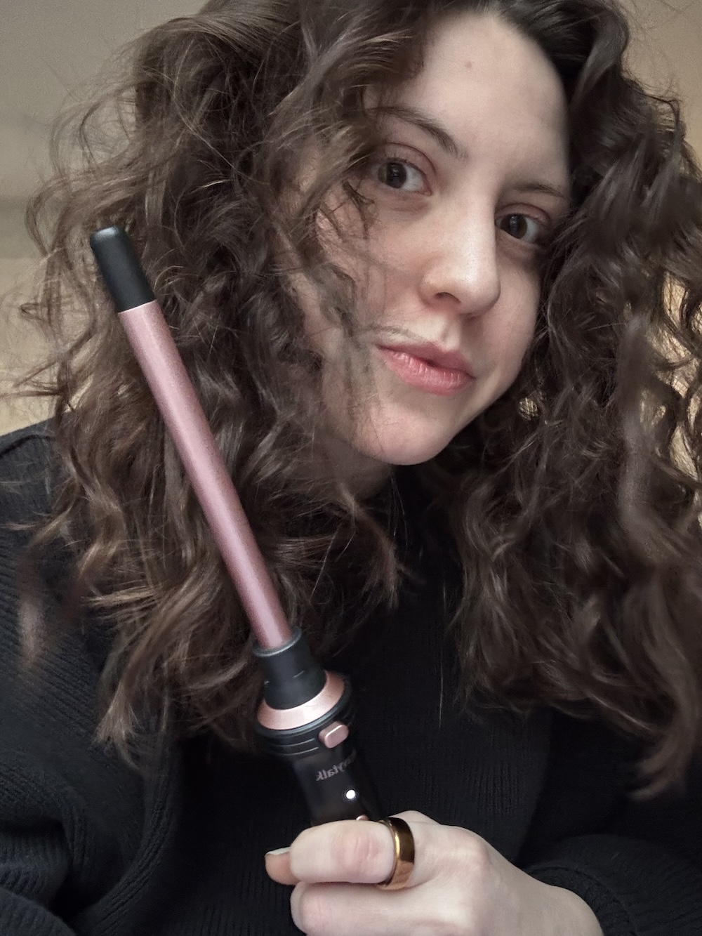 Sophia Vilensky holding her skinny-barrel curling wand.