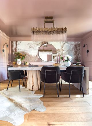A pink dining room with a feature wall of wallpaper