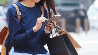 Woman looking at mobile phone and holding shopping bag 