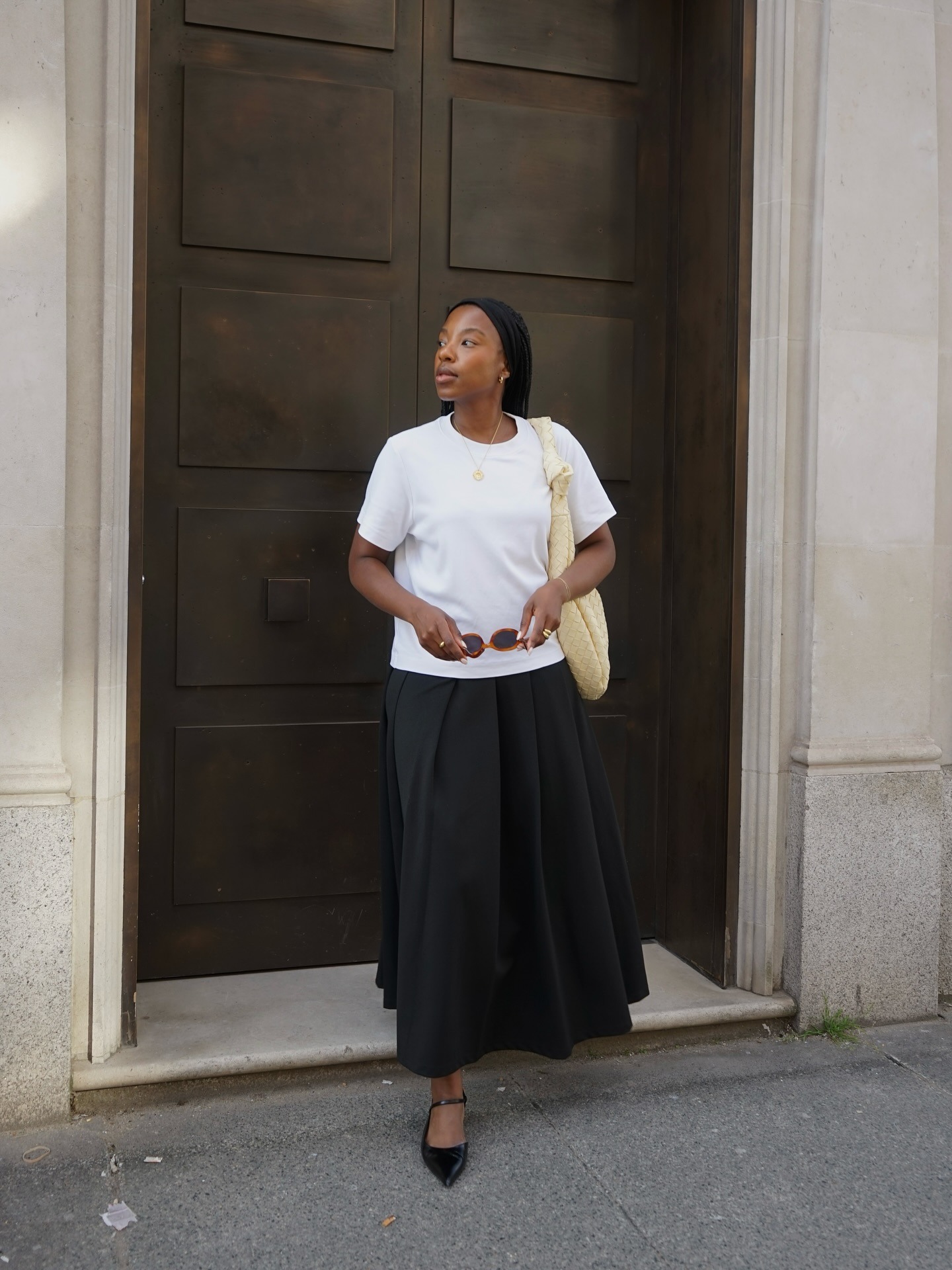 Taffy wears a white T-shirt, black pleated skirt and black ballet flats