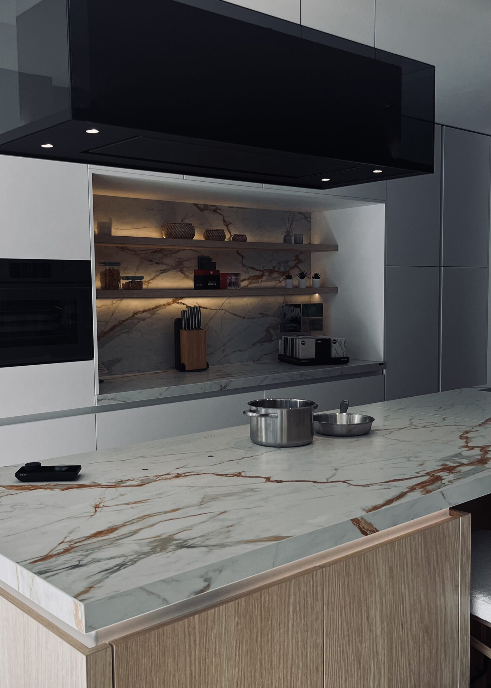 Novy Undercover hob in a white kitchen countertop with gold veining, and a black induction fan above
