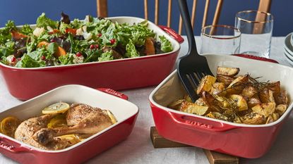 STAUB Ceramique set in red with a roast chicken, roast potatoes, and a salad in them