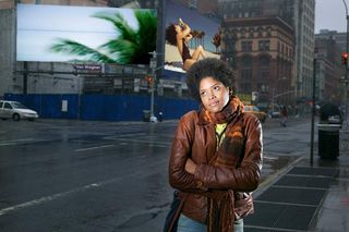 A woman daydreaming while standing on a city street.