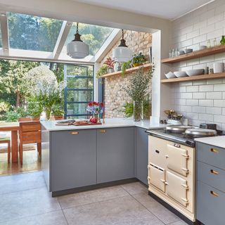 A contemporary kitchen with skylights, white pendant light fixtures and cream aga cooker