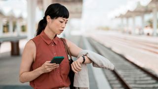 Woman looking at watch on wrist with phone in hand