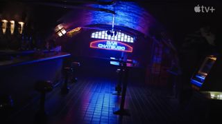 A dark bar with a neon sign in the background