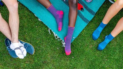 Best walking socks: Three pairs of legs on the grass wearing the best walking socks by Darn Tough