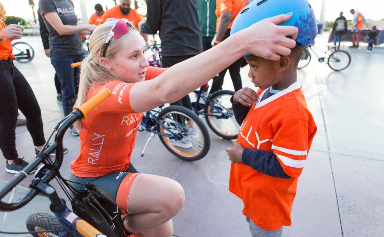 Rally Cycling's Megan Jastrab helps fit a helmet at the Rally Health bike build