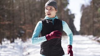 A woman dressed for winter runs in the snow