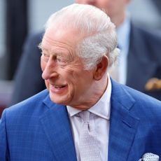 King Charles wearing a blue suit smiling