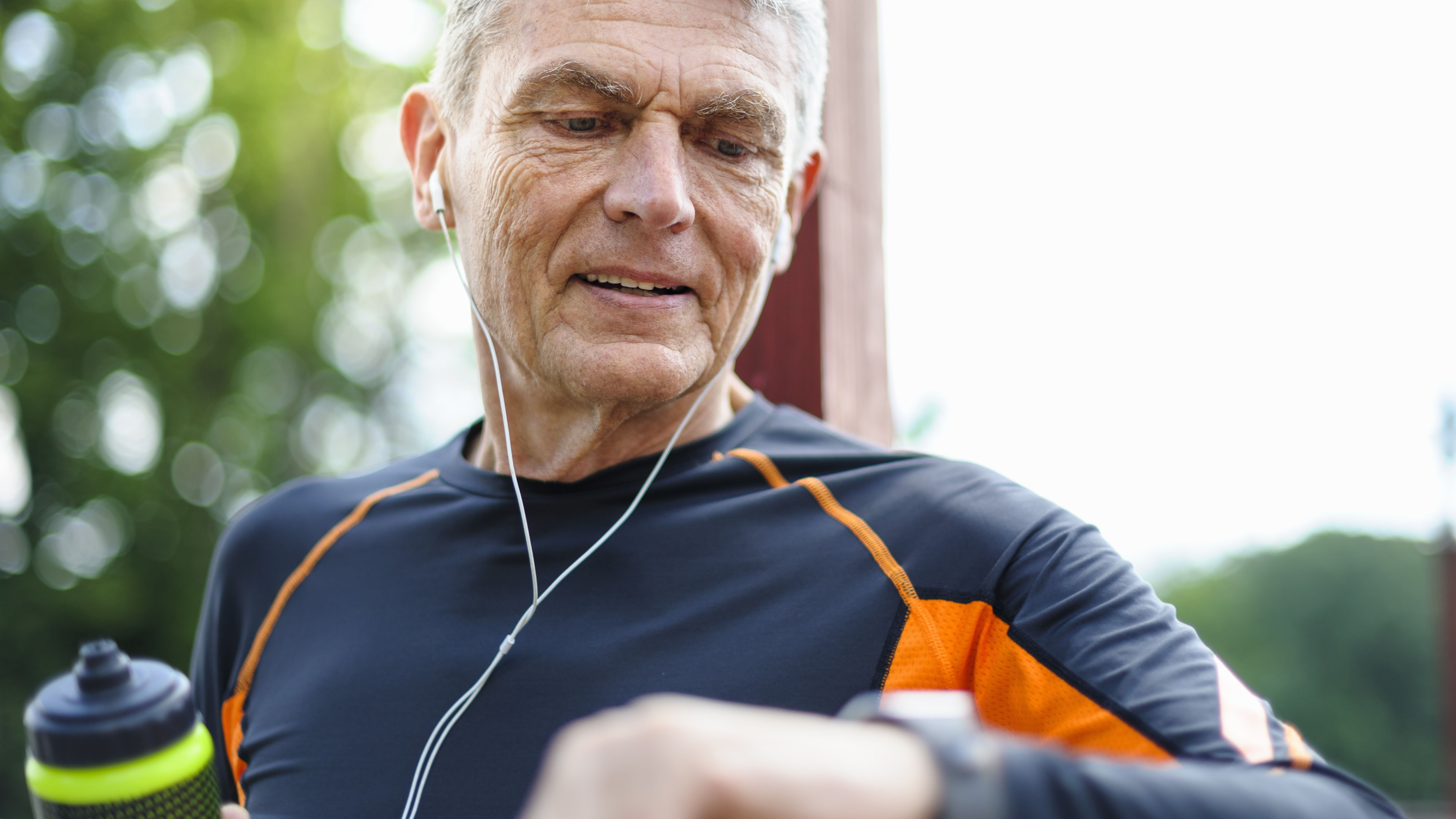 A man is wearing headphones and looking at a fitness tracker