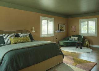 A bedroom with yellow walls, a green painted ceiling, and a bed dressed with green sheets