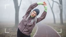 Woman in workout clothes standing on a foggy path in winter, stretching after learning does working out help hangovers