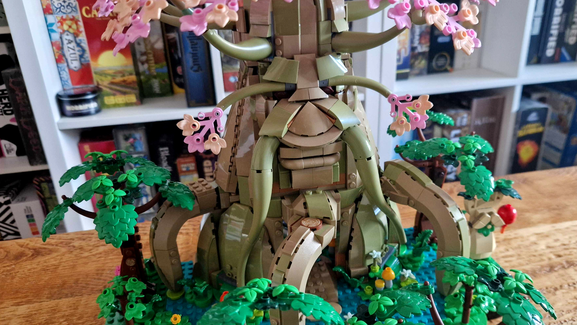 The Great Deku Tree Lego set on a wooden table, in front of a shelf of board games
