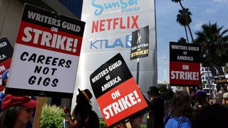 An image of striking writers' placards being held in front of Netflix's LA-based studio