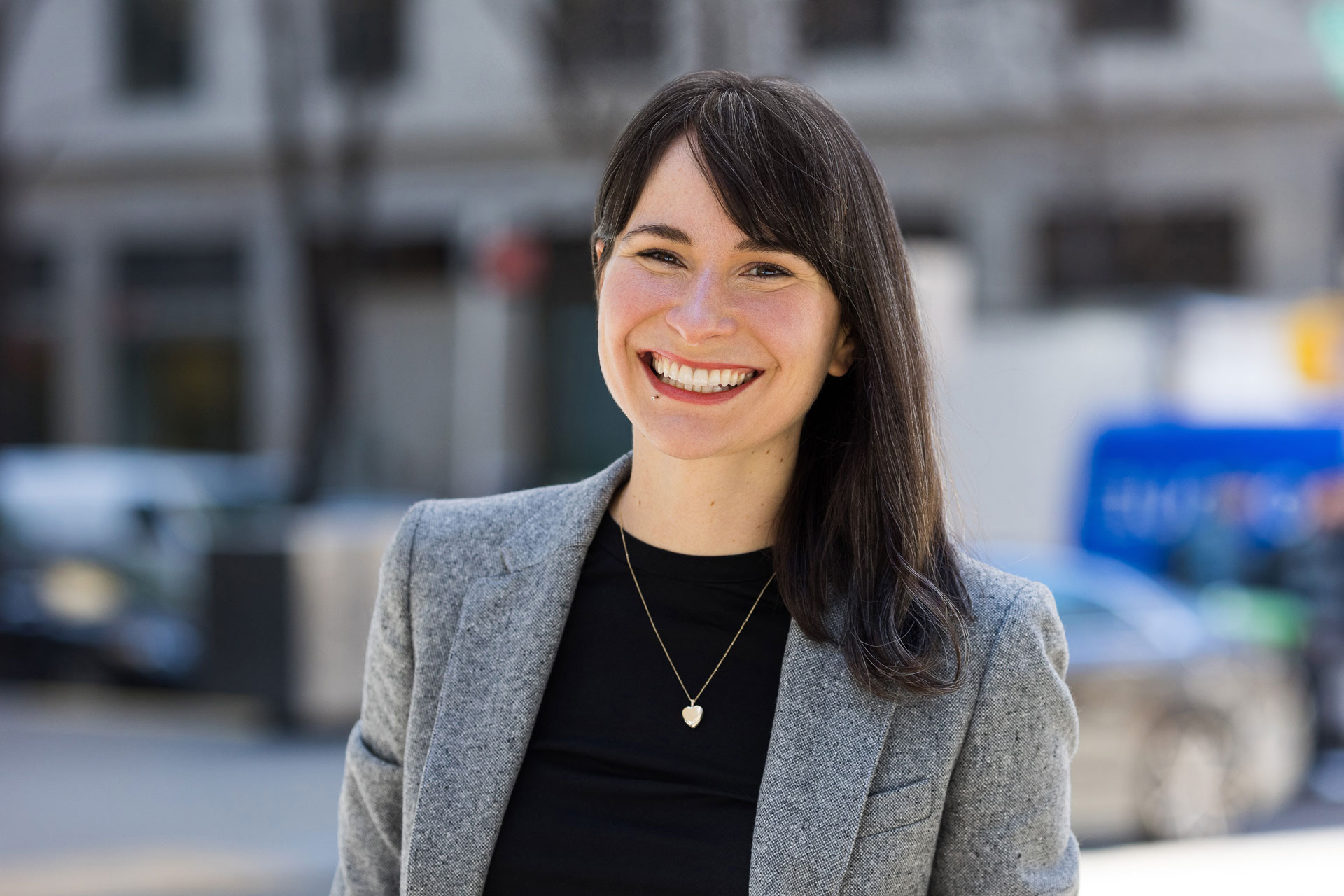 woman smiling wearing a suit jacket and a necklace and top