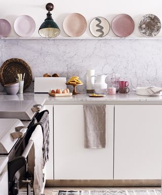 Pink kitchen color ideas in a white scheme with a selection of pale pink plates displayed on open shelving.